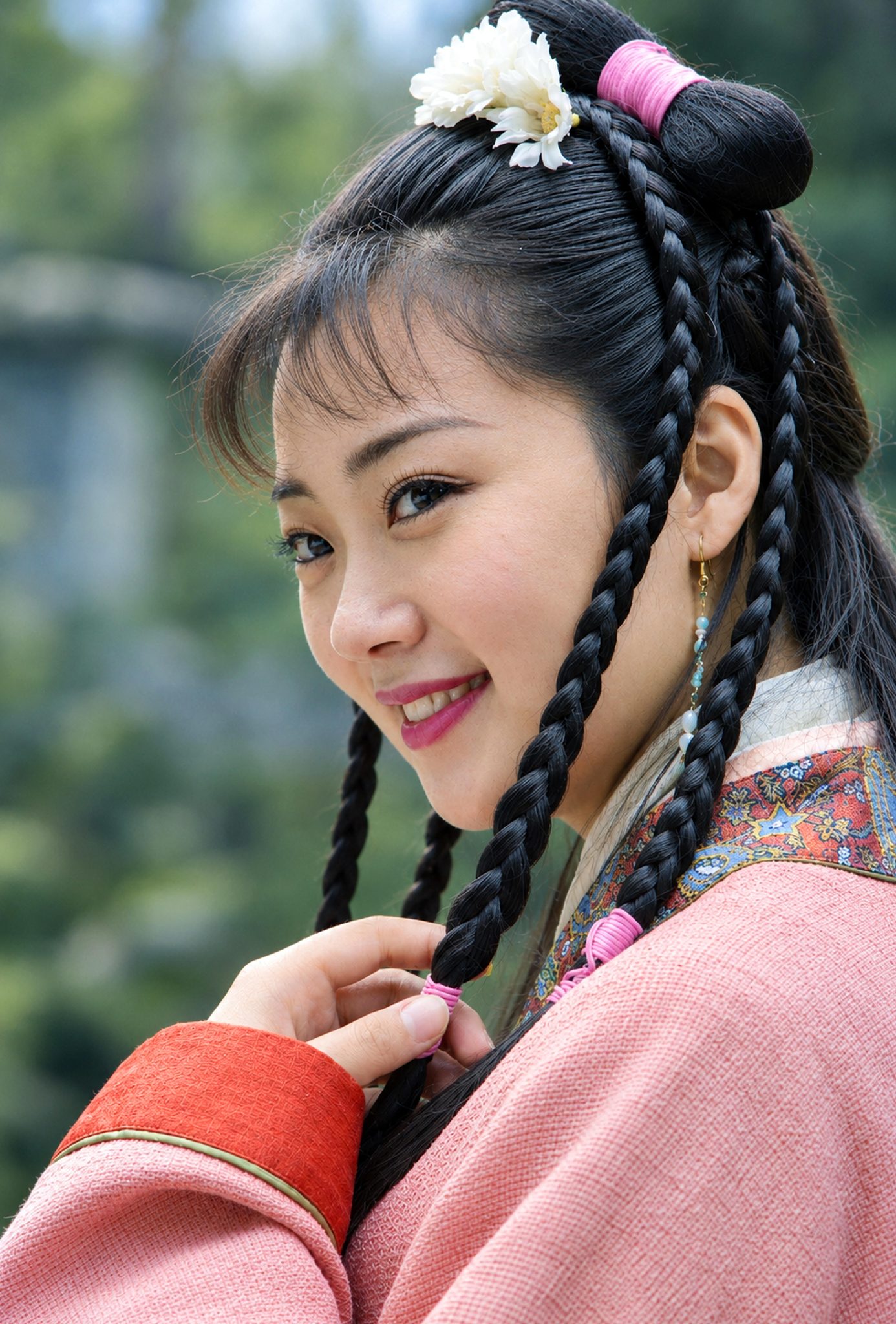 电视剧《乞丐皇帝朱元璋》剧照：梳着双辫、发间簪一朵白花的年轻女子，身穿粉色古装戏服，回头望向镜头微笑