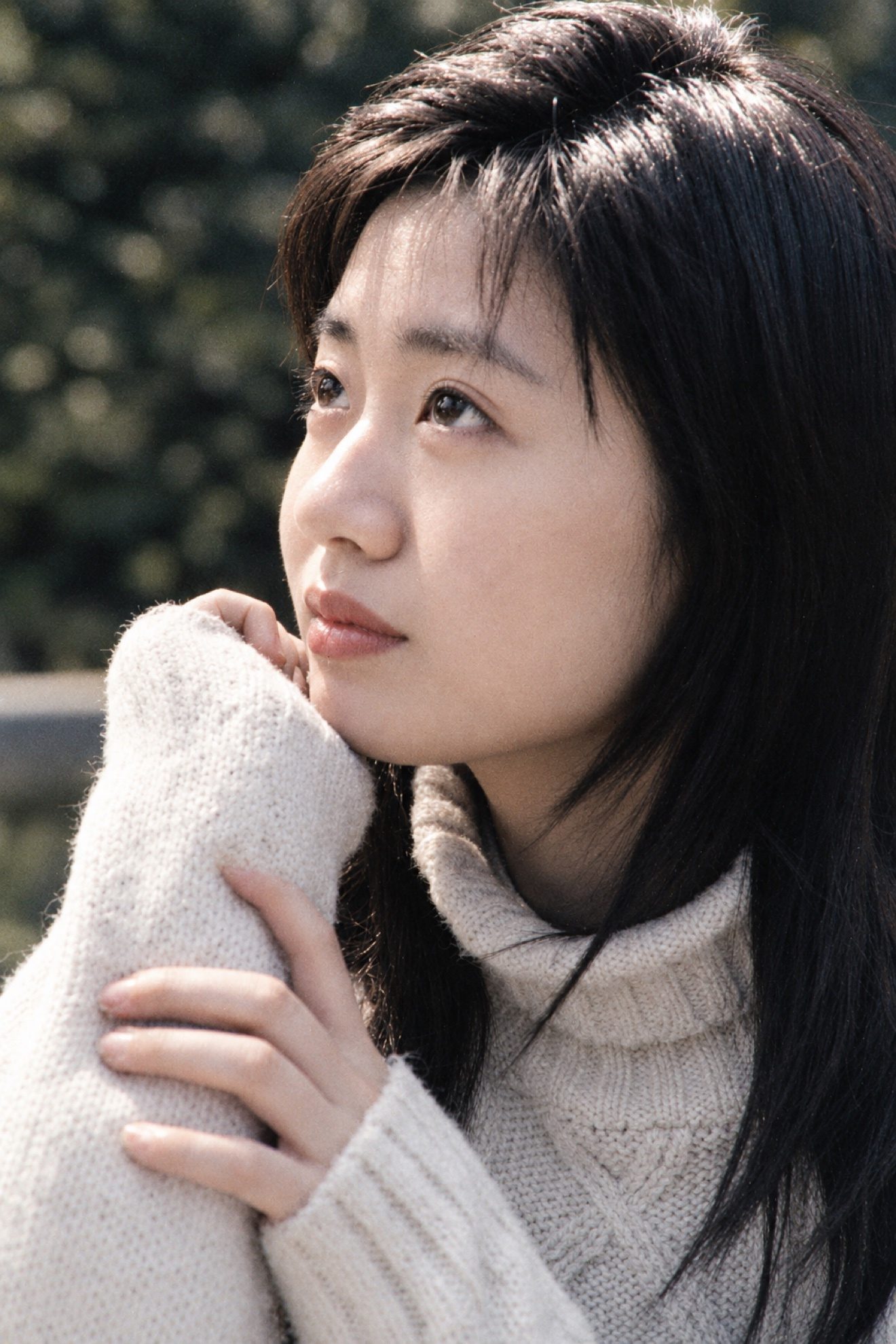 彩色照片：米色高领毛衣的年轻女子侧脸特写