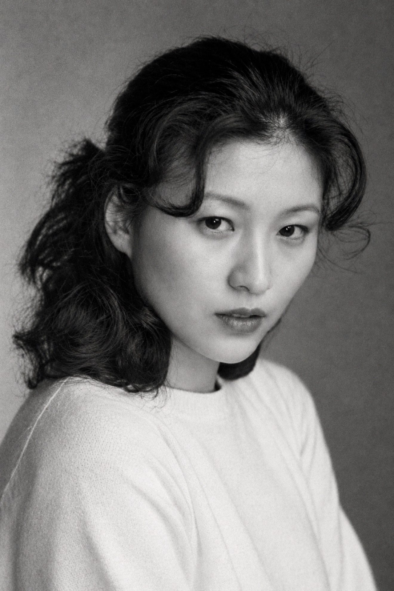 黑白照片：身穿白色毛衣的女子近景，回头望向镜头