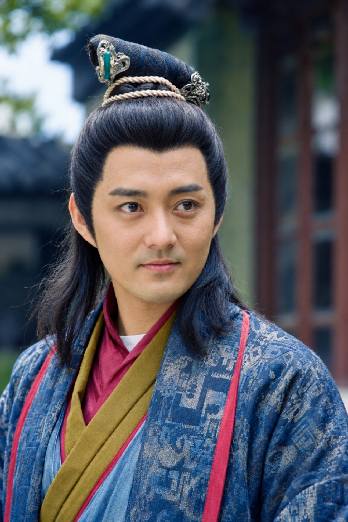 彩色照片：梳着古装发髻、簪着玉簪的男子身穿蓝纹长袍，户外近景