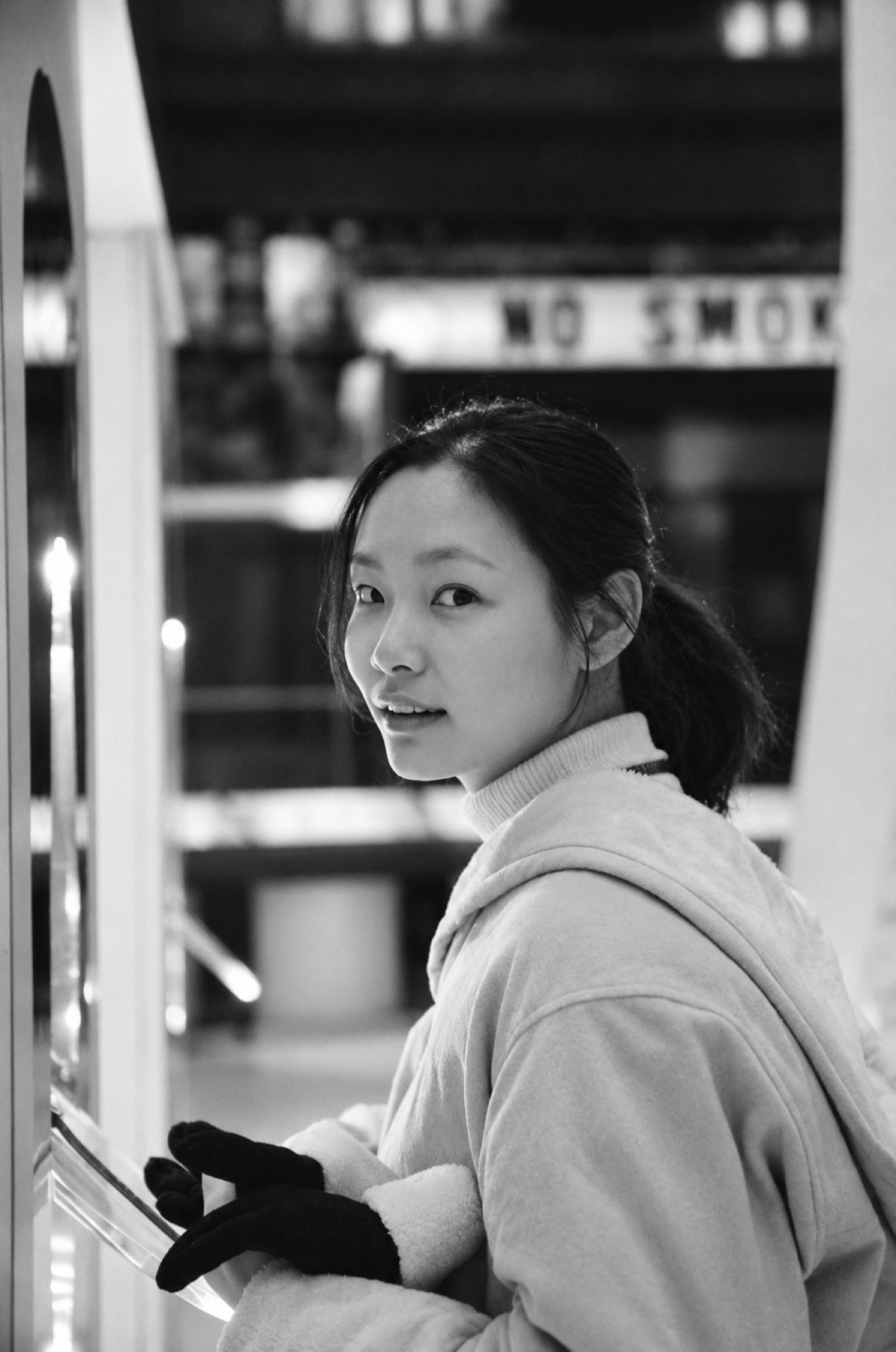 黑白照片：身穿白色外衣的女子回眸望向镜头，面带微笑