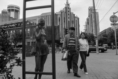 黑白照片：淮海路1996，街边立着一尊打电话的女子塑像，行人往来，身后高楼林立